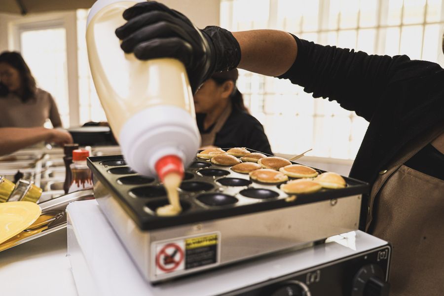 Mini pancake batter being piped onto the griddle